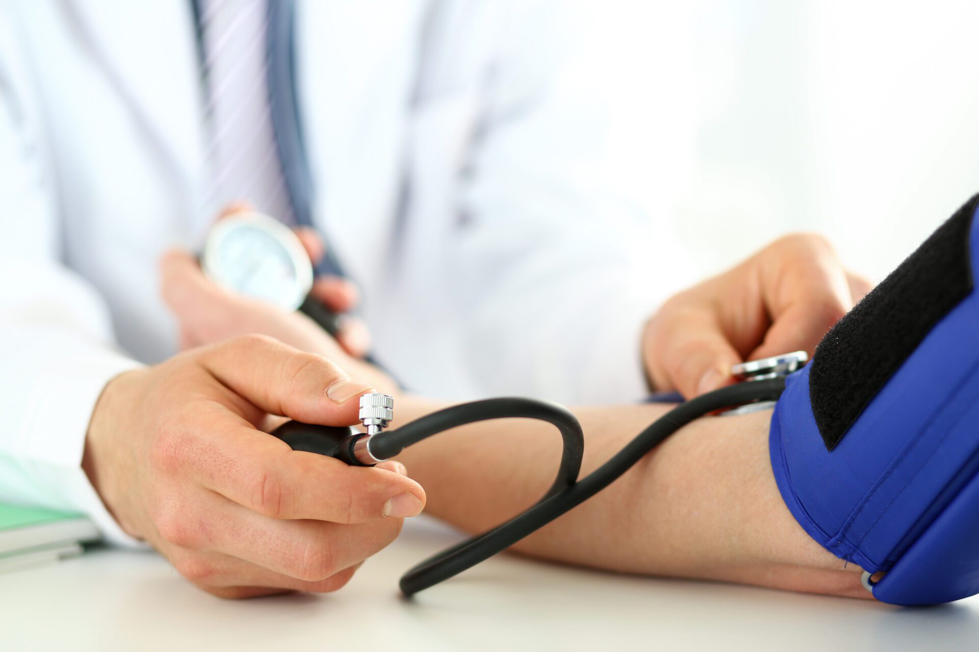 Doctor helping man Close-up of specialist's hands performing blood pressure check procedure with